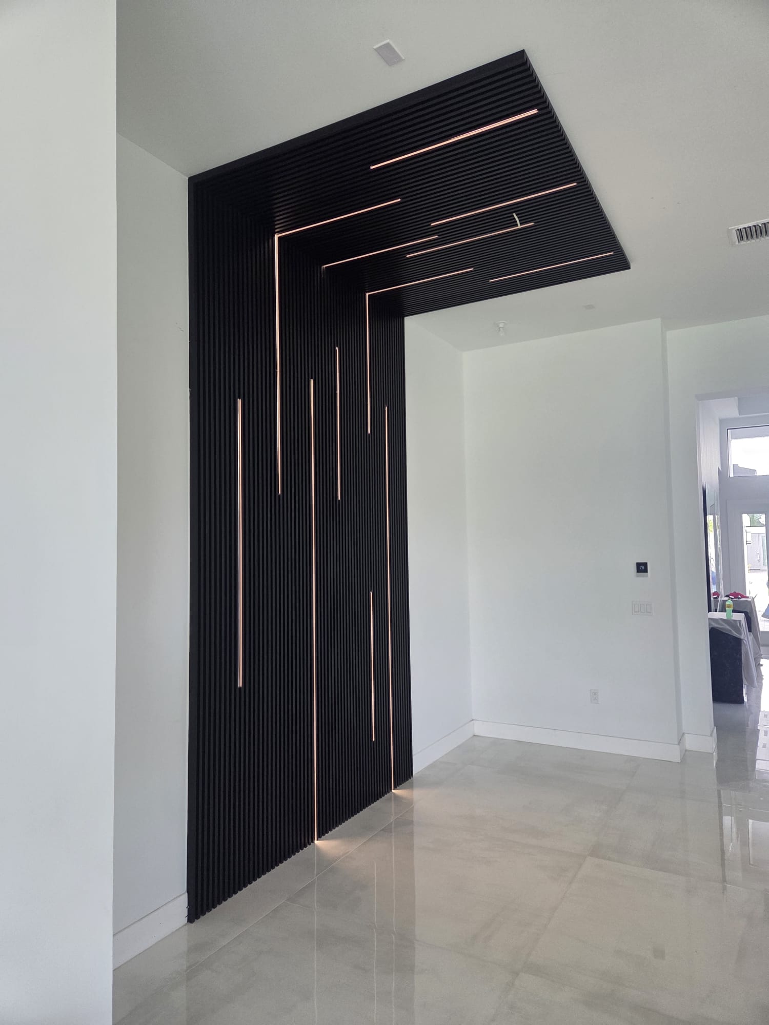 Custom decorative wall panel with integrated linear lighting, installed by COPLASA